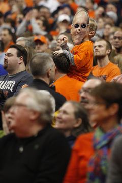 A young fan sits on his father's shoulders and cheers with a mask of Syracuse head coach Jim Boeheim over his face during the second half.