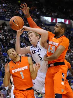 Connecticut swingman Niels Giffey attempts to drive through Syracuse guard Michael Carter-Williams and forward James Southerland, but has the ball knocked away.