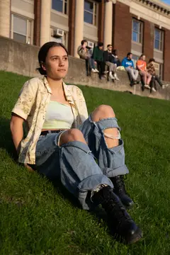 A portrait of ESF student Fiona Koye sitting on a grassy hill facing the live music.