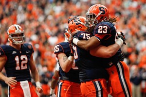 Prince-Tyson Gulley (23) celebrates with Zack Chibane (75) during Syracuse's upset win over Louisville on Nov. 10. The Orange clinched a share of the Big East championship Thursday when Louisville defeated Rutgers.