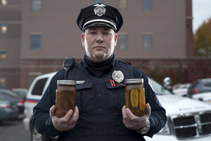 Officer Ryan Zarnowski of the Department of Public Safety holds two of his spicy products; a jar of stuffed peppers and a jar of spiced pickles. 
