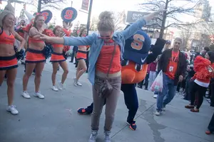 Sarah Eckhardt, a freshman at Syracuse University, dances with Otto the Orange outside of The Hudson Grille in Atlanta Georgia.