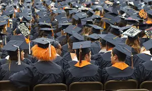 Undergraduate students from the College of Arts and Sciences sit on the turf in the Carrier Dome on Sunday morning as a part of the commencement ceremony. 