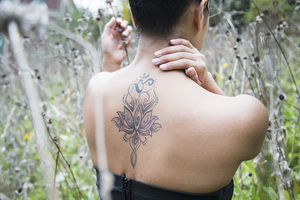 Deborah Thach's fourth tattoo depicts a lotus flower blooming into an Om sign on her upper back. Her other tattoos include the words 