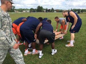 A group of Syracuse players works through an exercise of moving a 165-pound dummy across a field. 