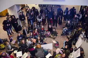 Student protesters sit in the lobby of Crouse-Hinds Hall shortly after entering the building on Monday afternoon. The students slept over in Crouse-Hinds on Monday night and plan to stay until at least Thursday.
