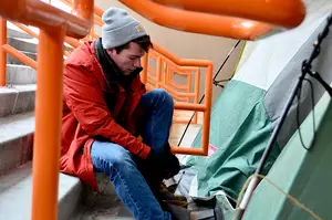 Davis Hovey, a junior broadcast and digital journalism major, ties his boot outside of his tent in Boeheimburg near Gate E of the Carrier Dome. Hovey is camping for the third time in his college career, and said “it’s just tradition at this point.