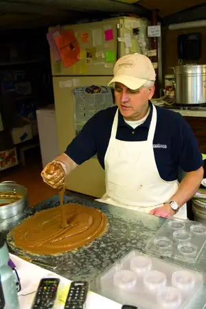 Steven Andrianos cools chocolate before pouring it into a mold featuring the logo of a corporate client who ordered the candy.