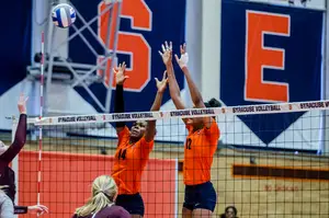 Jalissa Trotter (14) and Amber Witherspoon jump up to block a hit by Colgate on Sunday at the Women's Building. SU struggled turning blocks into offense in the loss.