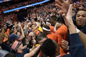 Security guards attempt to hold back fans charging the court from reaching Syracuse's Dajuan Coleman.