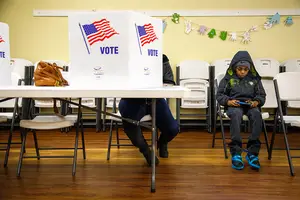 Joshaun Reese waits for his mother Tammy to finish filling out her ballot on Election Day.