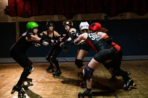 The skaters of Assault City Roller Derby work on a jamming drill. Katpiss Neverclean, wearing a gold helmet, is a jammer for the team.