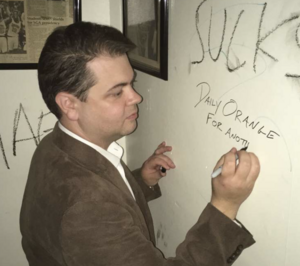 Dave Levinthal signs the wall at 744 Ostrom Ave. during the alumni goodbye celebration last fall in Syracuse.
