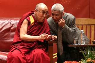 The Dalai Lama consults his translator, who whispers in his ear moderator Ann Curry's question.