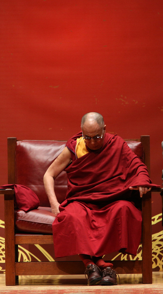 The Dalai Lama takes off his shoes at Monday's morning panel. 