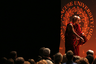 The Dalai Lama is helped out from behind a curtain onto the stage in Goldstein Auditorium.