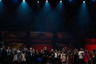 The entire cast of One World Concert artists performs together on stage.