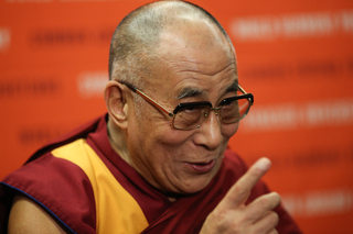 The Dalai Lama points as he speaks at a press conference before the One World Concert.