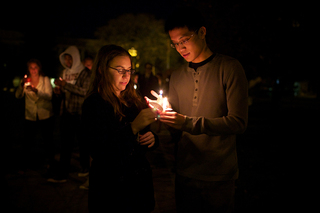 Lyndsay Katz, a senior advertising major. helps to relight Jodie Huang, a senior finance major's candle while walking from Hendricks Chapel to the Wall of Remembrance. 