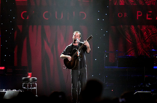 Dave Matthews performs at the center of the stage.