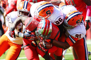 (From left) Syracuse linebacker Siriki Diabate and defensive linemen Jay Bromley and Brandon Sharpe gang tackle a Rutgers player.