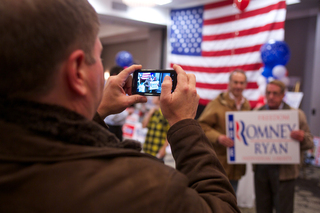 Bob Fyffe photographs friends Philip Rosenfeld (left) and Chet Madej (right) with a Mitt Romney poster Tuesday night.
