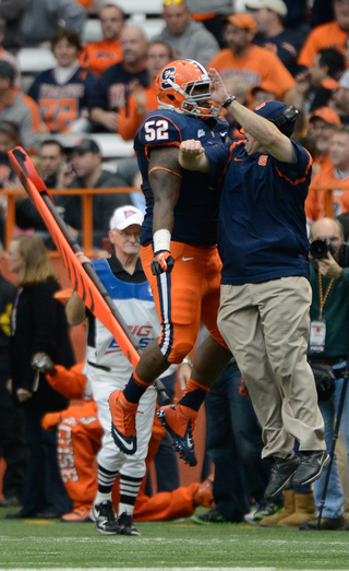 Syracuse defensive tackle Eric Crume and an Orange assistant coach chest bump in celebration.
