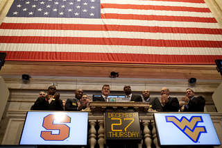 Syracuse quarterback Ryan Nassib and West Virginia quarterback Geno Smith stand in the center of representatives from both teams as they ring the opening bell at the New York Stock Exchange.