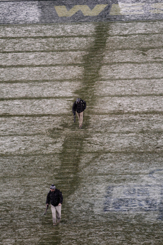 Workers blow snow off the lines on the field in the fourth quarter. 