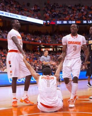 Syracuse University guard Michael Carter-Williams (1) gets helped up by teammates Baye Moussa Keita (12) and Jerami Grant (3).