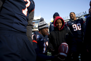 Syracuse linebacker Marquis Spruill takes a football to autograph from a child at Friday's 