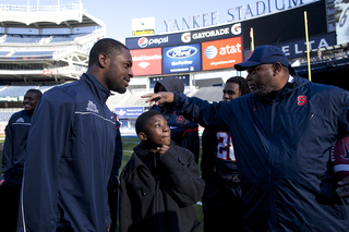 Syracuse cornerback Keon Lyn and secondary coach Donnie Henderson chat with a child attending the 