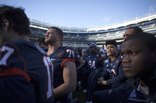 Offensive linemen Zack Chibane and Ivan Foy look up as head coach Doug Marrone speaks to the team and area youths at Yankee Stadium Friday.