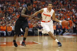 Syracuse point guard Michael Carter-Williams runs down the court in the second half as he is guarded by Cincinnati guard Ge'Lawn Guy.
