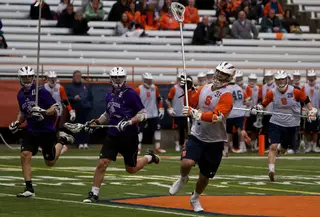 Syracuse defender Griffin Vehar holds his stick high and he runs downfield.