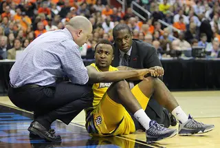 Junior Cadougan #4 (C)of the Marquette Golden Eagles looks to head coach Buzz Williams (L) after an injury in the game.