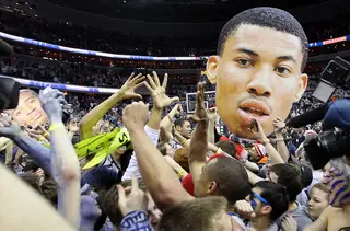 Fans celebrate on the court following Georgetown's win, including one wielding a cardboard cutout of Otto Porter.
