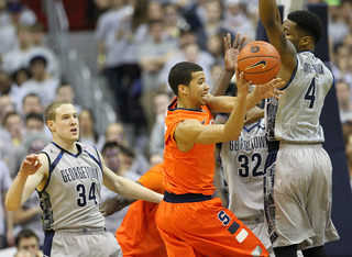 Michael Carter-Williams looks to pass the ball back out as he is swarmed by Georgetown defenders.