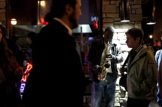 David Farrow, a local Atlanta street performer, lulls the street with his saxophone late in the evening as fans enjoy the Atlanta nightlife. 