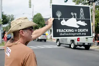 Albert Crudo holds up a sign to passing traffic protesting against hydrofracking's effects on the environment.
