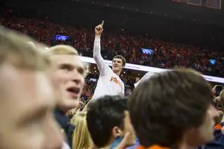 A Virginia fan sits on top of the court-storming crowd and holds up a number-one sign. 