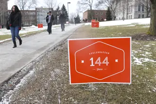 Students walk past 144th SU birthday signs in front of the Hall of Languages. Signs were posted all over campus by the Office of Alumni Relations.                          