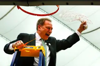 Michigan State head coach Tom Izzo waves the net in the air as spectators cheer.