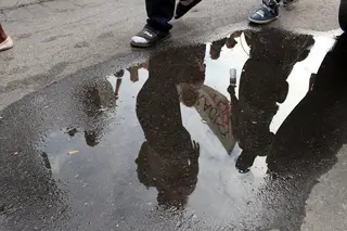 Reflections of the marching crowd show in the puddles on the road from earlier rain.
