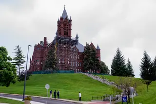 People stop to look at the scaffolding on the Crouse College building as workers continue to replace masonry and do other improvements to the historic building. Photo taken July 25, 2017
