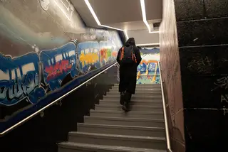 A student climbs up the graffiti-covered stairway from the underground lounge.