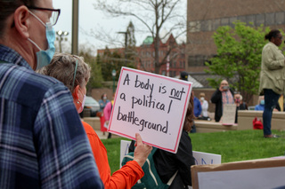 A woman holds a sign reading “A body is not a political battleground” in front of the James M. Hanley Courthouse. 