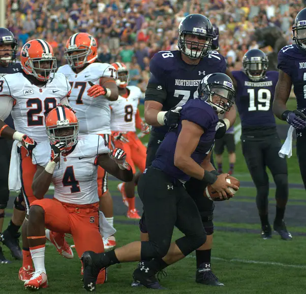 Northwestern quarterback Kain Colter celebrates as cornerback Brandon Reddish (4) and the rest of the Syracuse defense look on. Colter rushed for 102 yards to go along with 116 through the air.