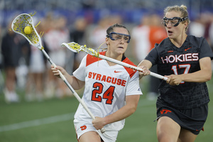 Emma Tyrrell (left) cradles the ball forward while Virginia Tech's Jordan Tilley attempts to steal possession. In the first quarter against the Hokies, Syracuse tied a season-low two goals before going on to win 14-12