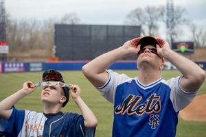 People travel hundreds of miles to cloudy Syracuse, NY in attempt to see a glimpse of the solar eclipse at complete totality. The Syracuse Mets invited fans of all ages to watch the eclipse and then enjoy a game afterwards.